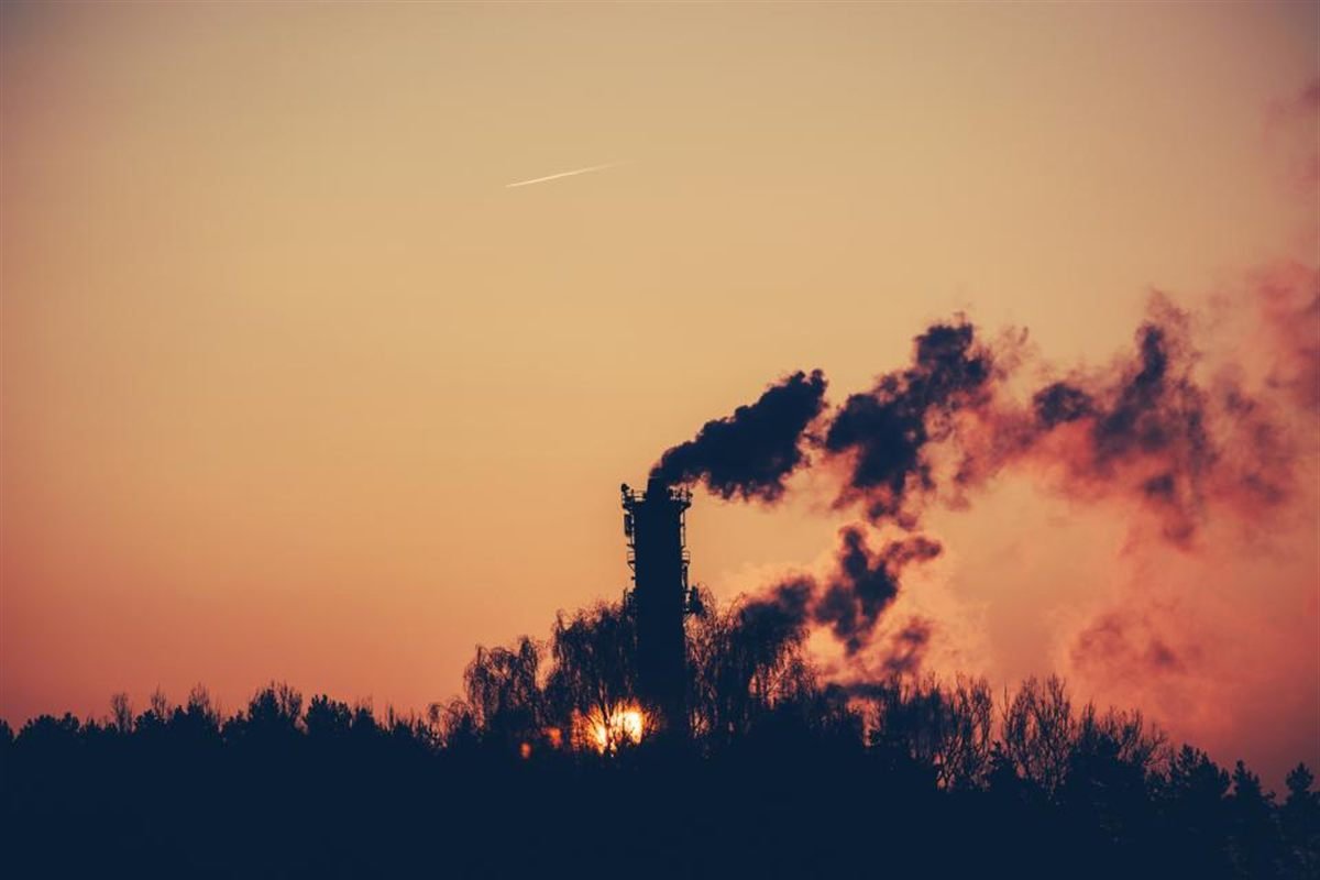 Industrial chimney emitting smoke against an evening sky