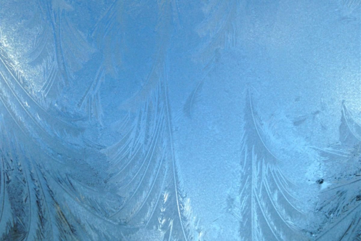 Frost patterns spreading across a window pane