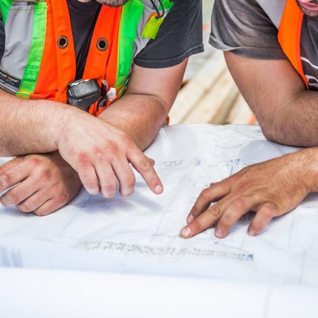 Two people in high-visibility vests studying a plan